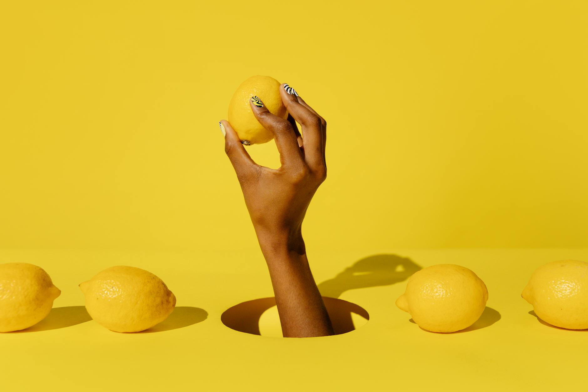 A fresh lemon held against a yellow background, symbolizing new beginnings and citrus vitality
