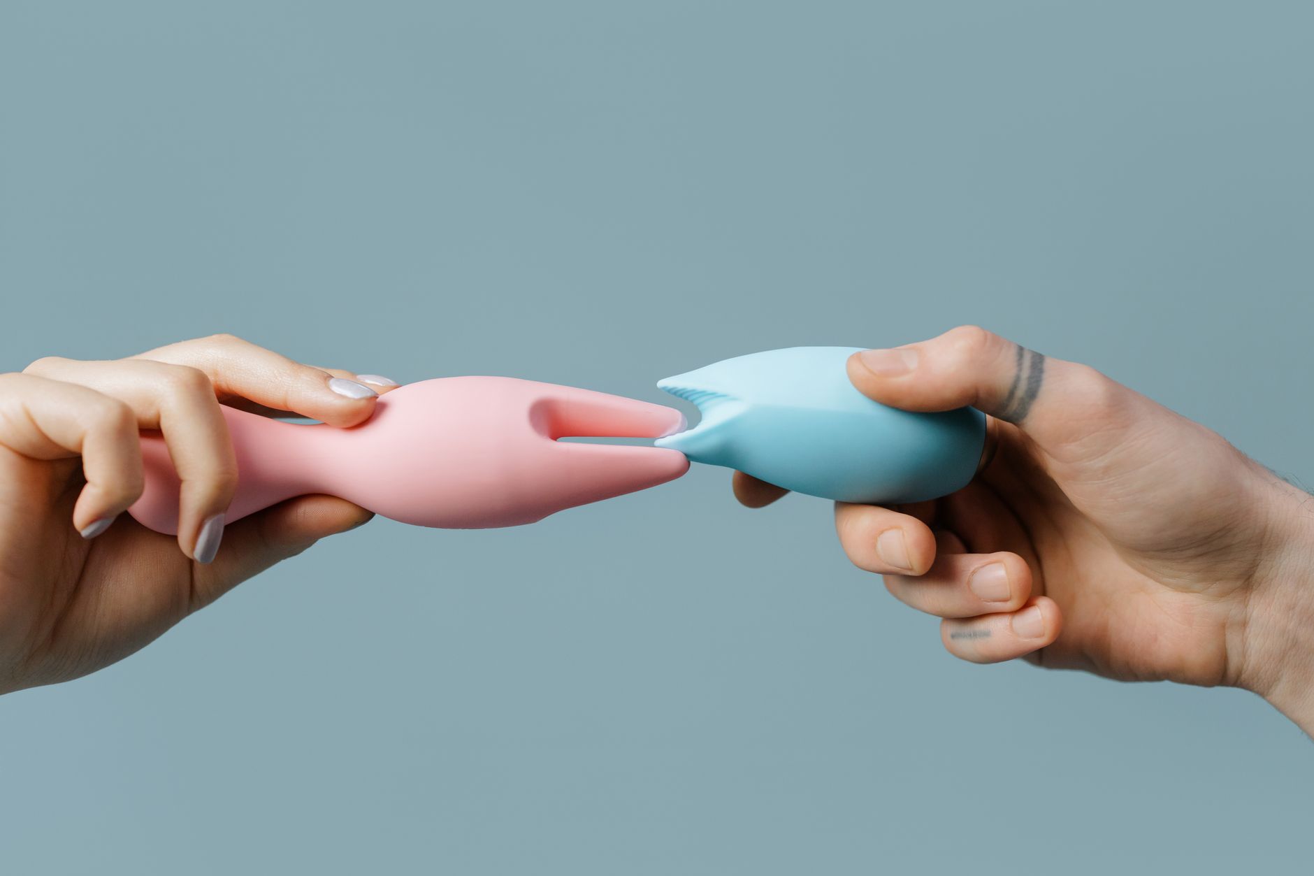 Close-up of a hand holding an orange vibrator against a minimalistic purple backdrop
