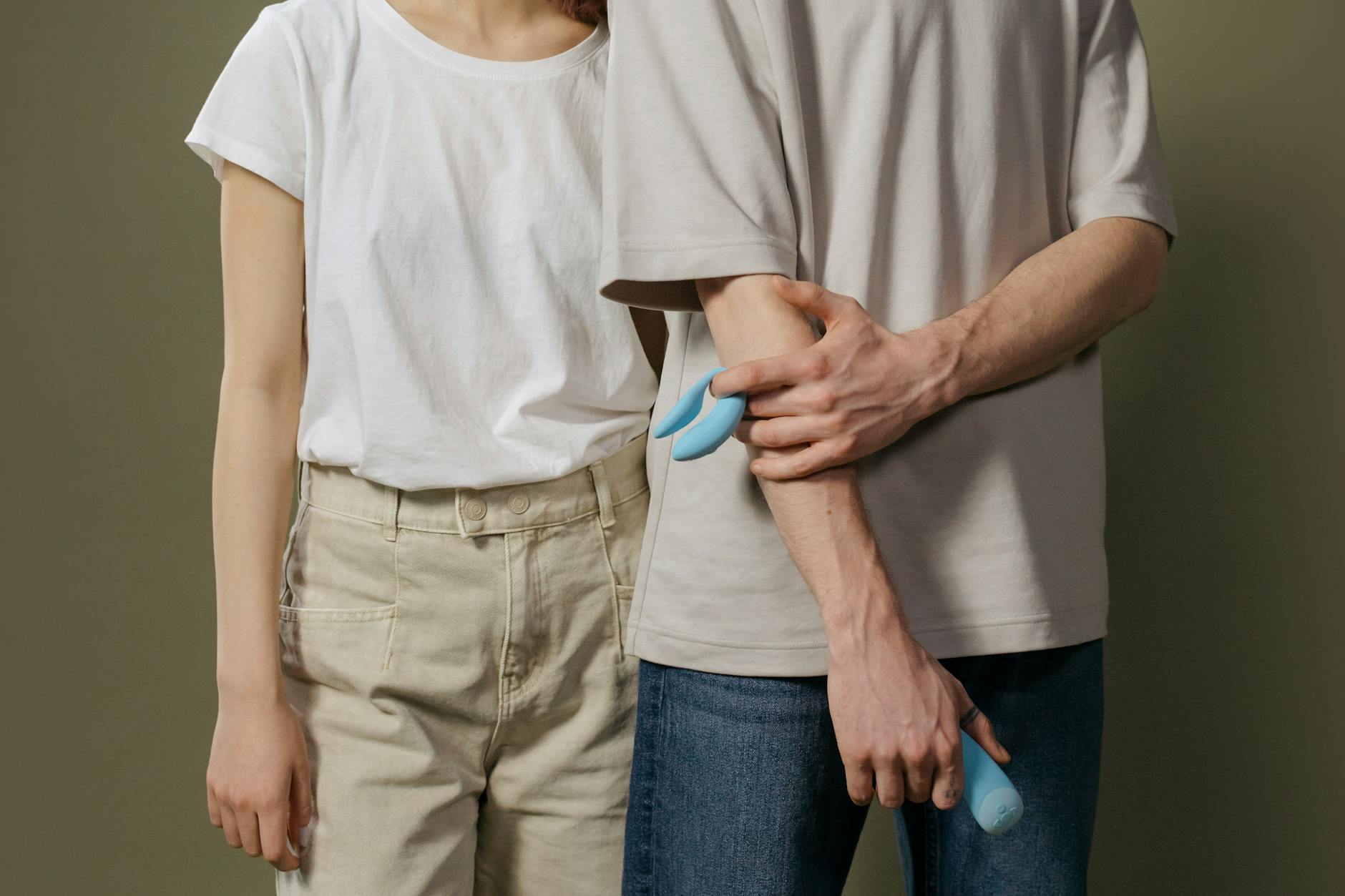 A hand holding an orange vibrator against a minimalistic purple backdrop, showcasing modern sensuality