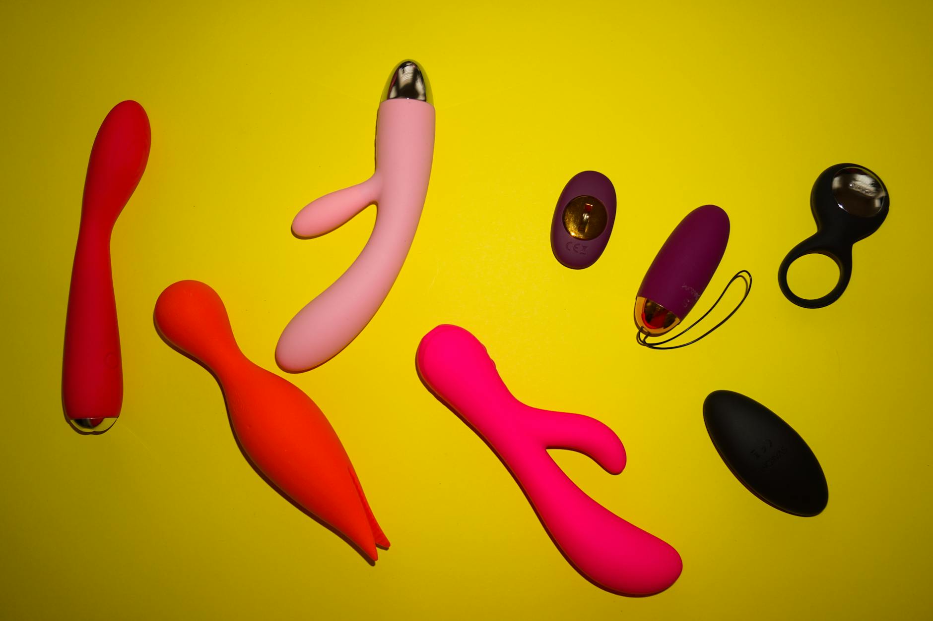 Vibrant photo of various lemon and colorful sex toys arranged on a bright yellow surface